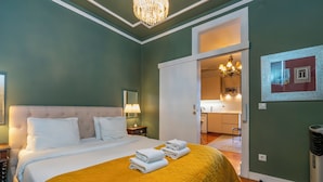 A neatly made bed with a yellow quilt, a bedside lamp, and a framed picture on the wall. - Portuguese Charm in Lisbon (Lisboa)