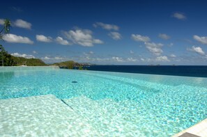 Una piscina con borde infinito, tumbonas