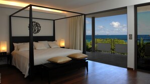 A four-poster bed with a view of the ocean.