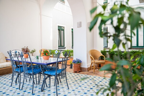 Relax in this serene patio area with a dining setup, featuring a round table and six comfortable chairs.
