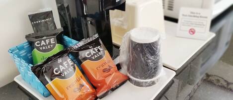 Un coin café équipé d’une machine à café, de gobelets jetables et de paquets de café de la marque Cafe Valet.