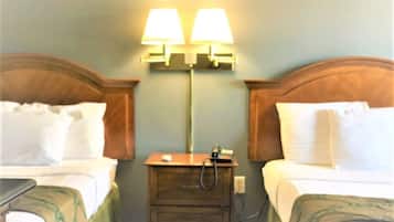 A hotel room with two beds, a nightstand, and two wall-mounted lamps.