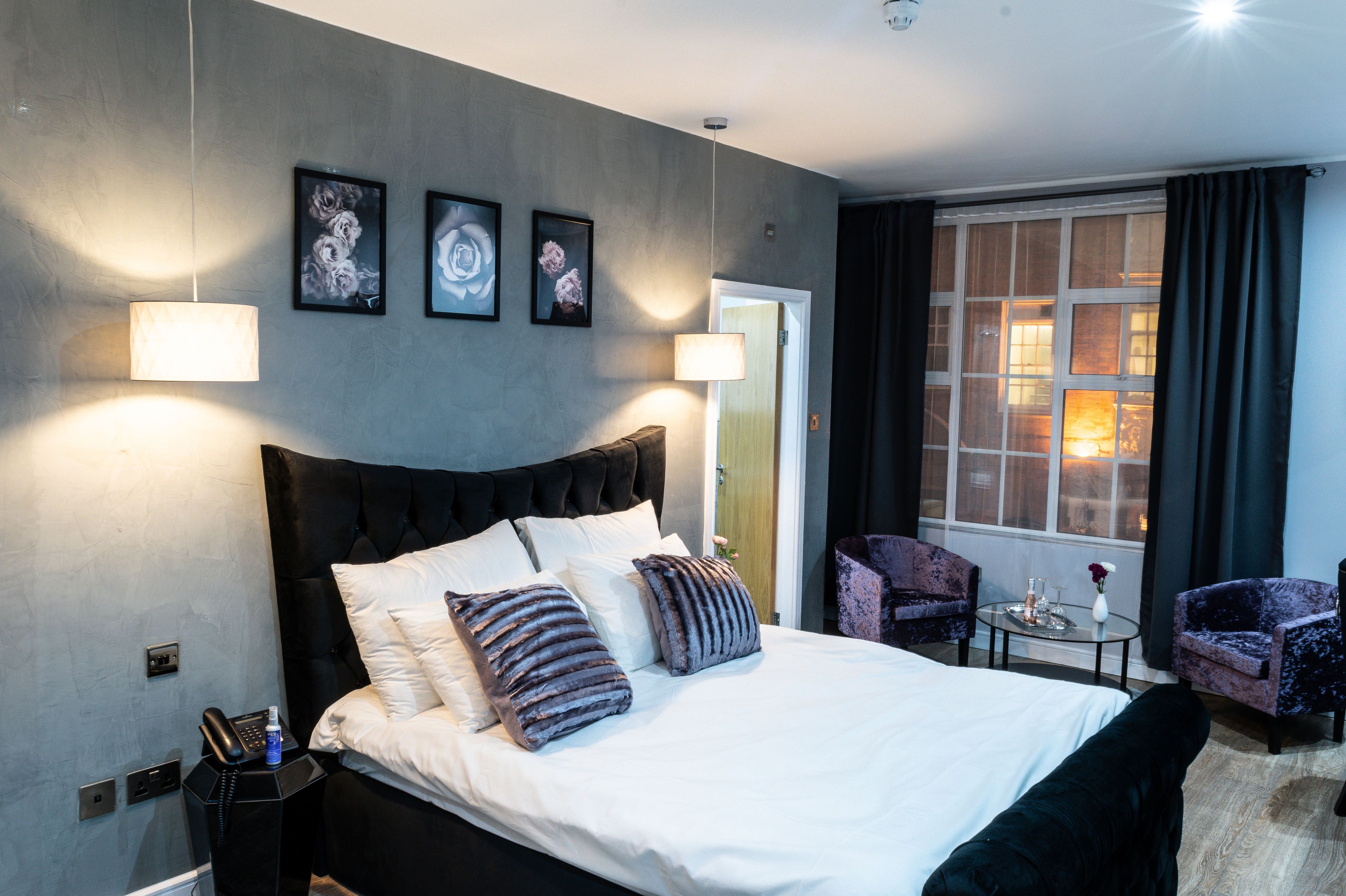 A modern hotel room with a large bed, two side tables, a chair, and a window with curtains.