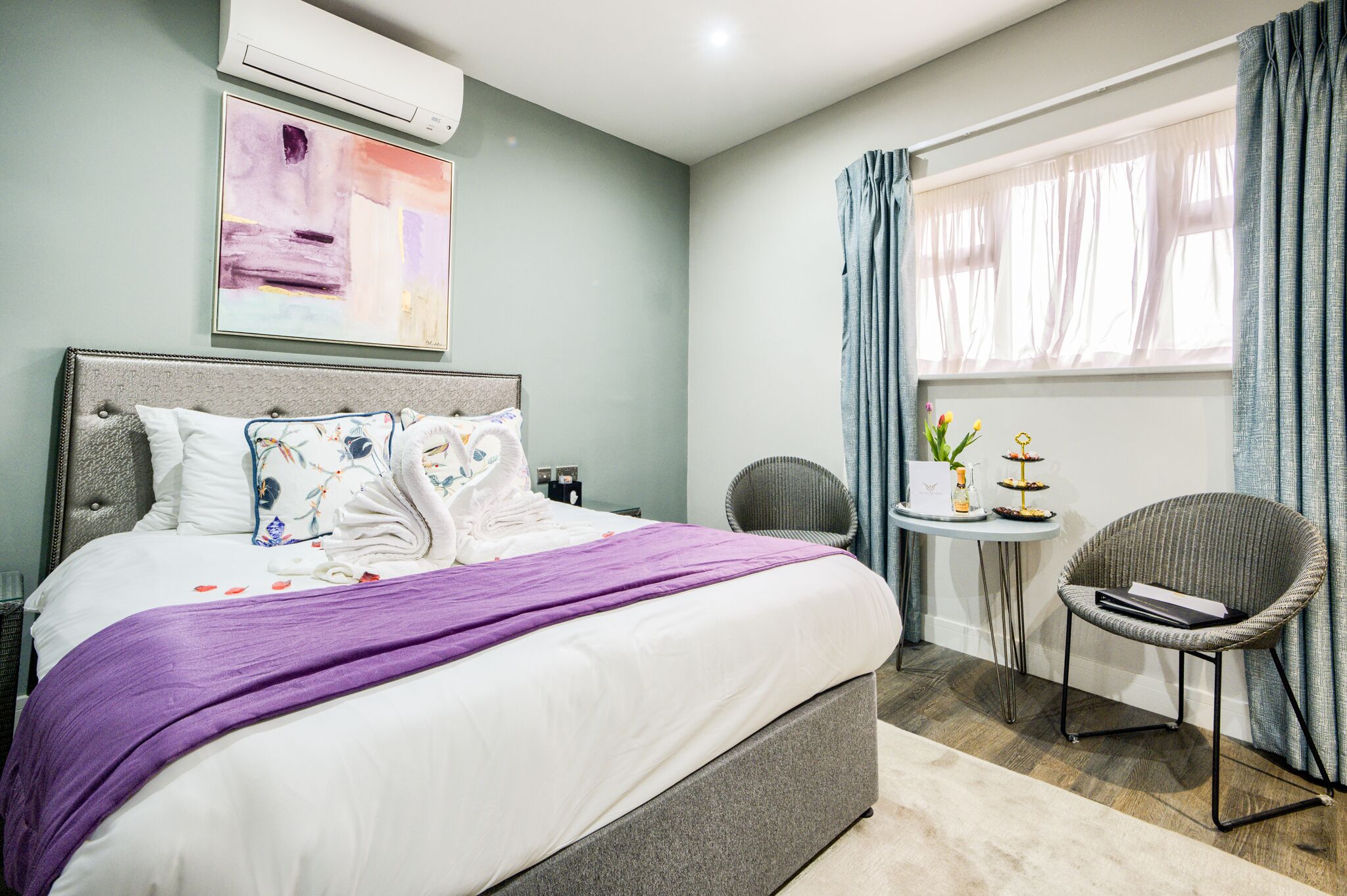 Een moderne slaapkamer met een groot bed, een klein nachtkastje, een stoel en een raam met gordijnen.