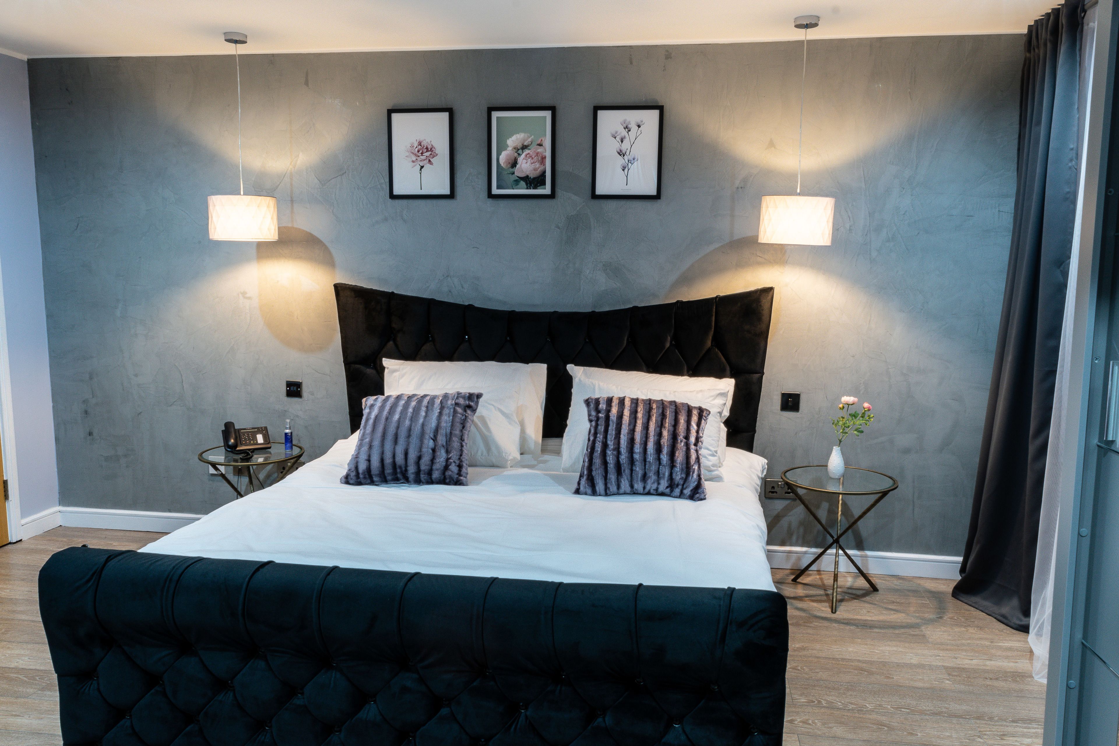 A modern bedroom with a large bed, two bedside tables, and a wall-mounted light fixture.