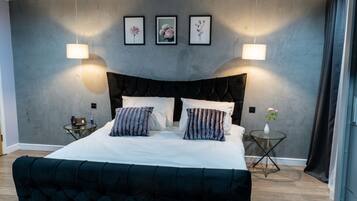 A modern bedroom with a large bed, two bedside tables, and a wall-mounted light fixture.