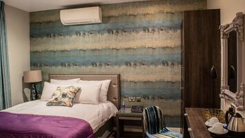 A hotel room with a bed, a nightstand, a chair, a desk, and a large wall mural.