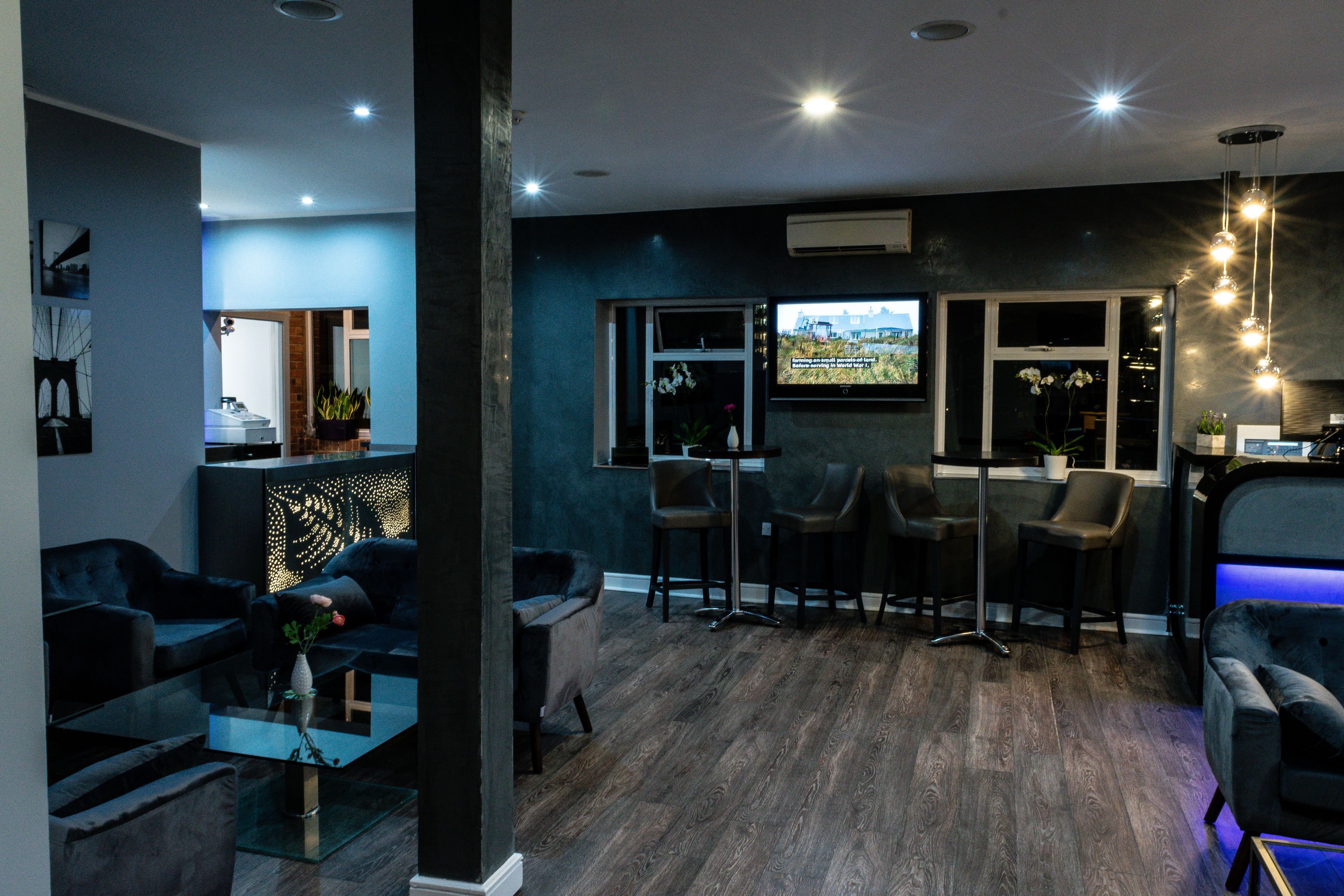 A modern living room with a dark blue wall, a glass coffee table, and a seating area with sofas and chairs.