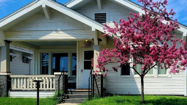 A two-story house with a porch, a small garden, and a pink flowering tree. - Butte Bungalow Home, Close to uptown- 2 bdrm, 2 bath, No Cleaning fee (Butte)