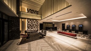 A spacious lobby with a checkered wall, a red bench, and a seating area with modern chairs. - The Rise Osaka Kitashinchi (Osaka)