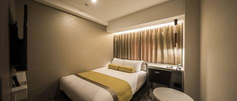 Una habitación de hotel con cama, escritorio, silla, mesita y televisor.