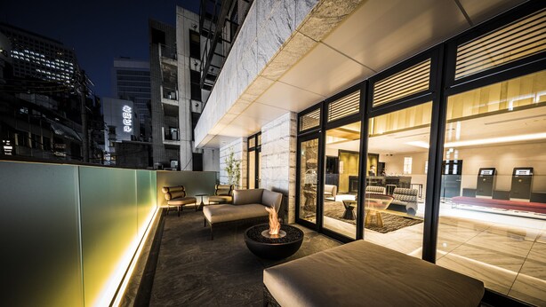 A modern outdoor seating area with a fire feature, comfortable seating, and a view of the cityscape. - The Rise Osaka Kitashinchi (Osaka)