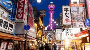 A bustling street with illuminated signs and a prominent tower in the background.