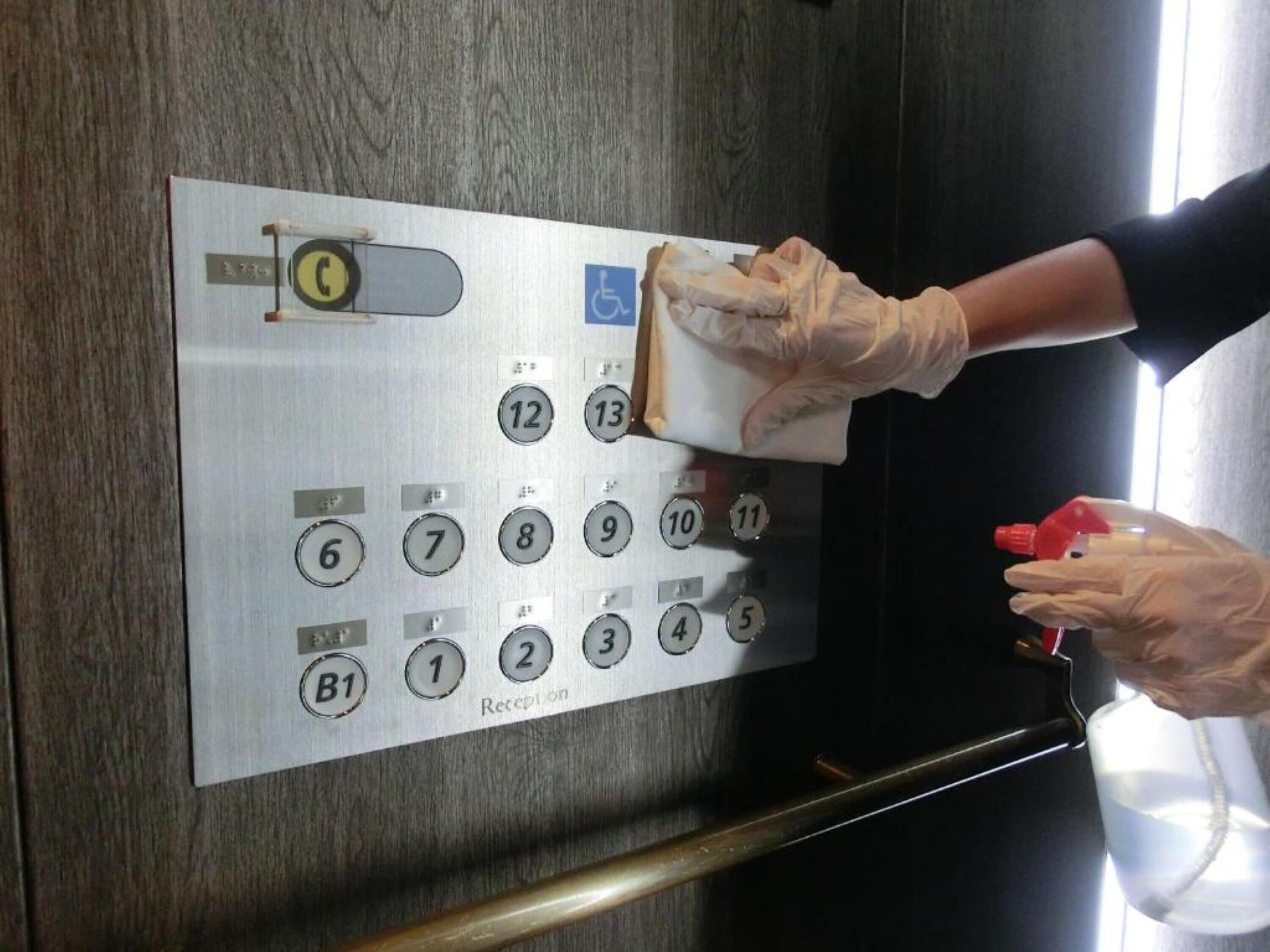 A person using an elevator control panel with numbered buttons and a wheelchair accessibility symbol.