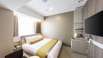 A hotel room with a bed, bedside table, TV, and a small desk with a chair.