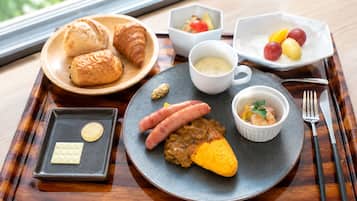 Uma bandeja com croissants, salsichas, um prato assado e pequenas tigelas de comida.