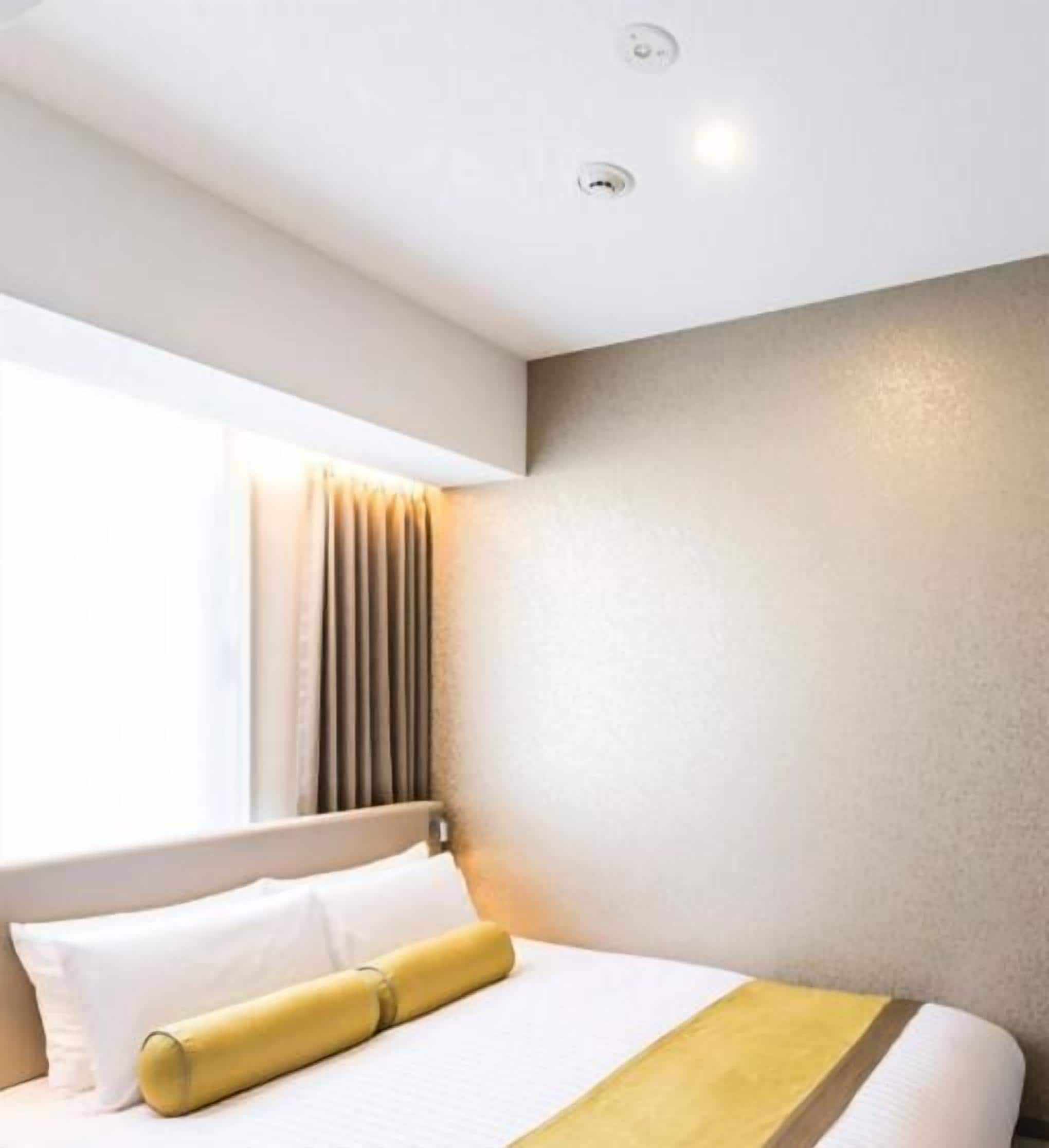 Ein Hotelzimmer mit Bett, einem Vorhangfenster und einer Deckenleuchte.
