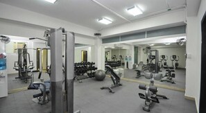 A gym with various exercise equipment, mirrors, and a weight rack.