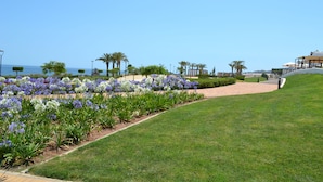 A landscaped garden with a pathway leading to a building with a covered seating area. - Apartment Costa Almeria San Juan de los Terreros (san juan de los terreros)