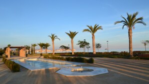 A landscaped area with a pool, palm trees, and a pergola. - Apartment Costa Almeria San Juan de los Terreros (san juan de los terreros)