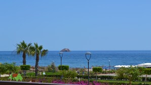 A coastal view with a beach, palm trees, and a distant island. - Apartment Costa Almeria San Juan de los Terreros (san juan de los terreros)