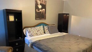 Un dormitorio con cama, cómoda, silla y un cartel en la pared.