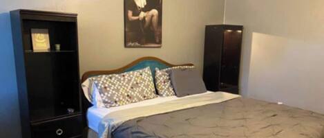 A bedroom with a bed, a dresser, a chair, and a poster on the wall.