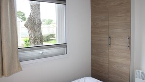 A bedroom with a window, a wooden wardrobe, and a bed.