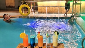 Una zona de piscina con bar y sillones de descanso.