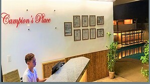 Un área de recepción con un mostrador, un letrero de neón que dice "Champion's Place" y varios certificados enmarcados en la pared.