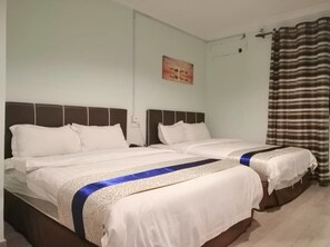 A hotel room with two beds, a painting on the wall, and a striped curtain.