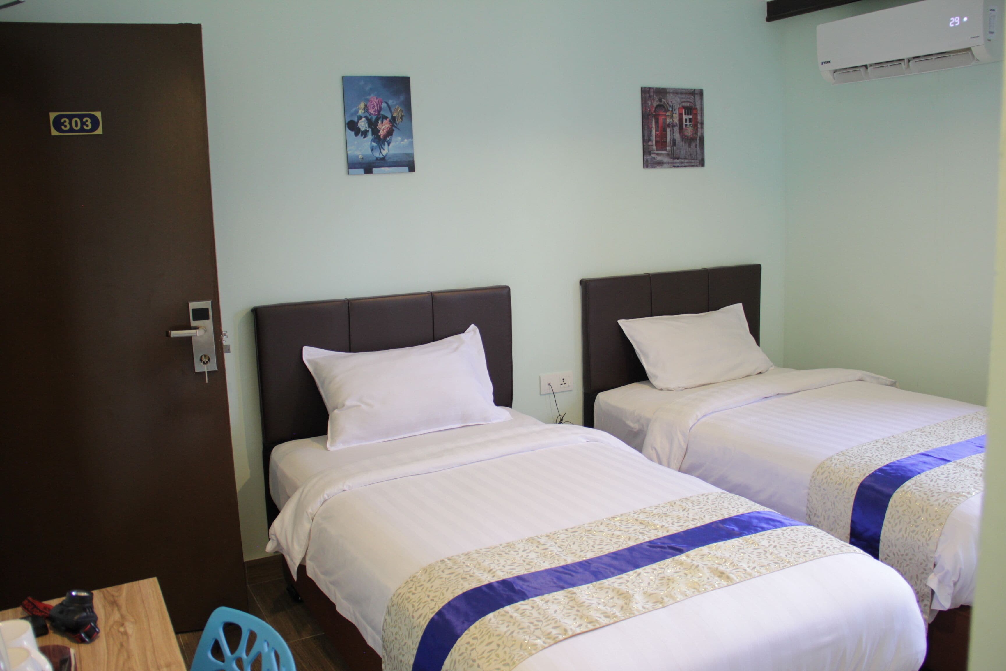 A hotel room with two beds, a wooden table, and a blue chair.