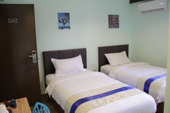 A hotel room with two beds, a wooden table, and a blue chair.