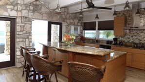 A kitchen with a stone accent wall, wooden cabinets, a central island with bar stools, and a ceiling fan.