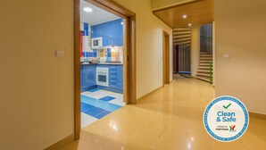 A hallway leading to a kitchen with blue cabinets, a microwave, and a stove.