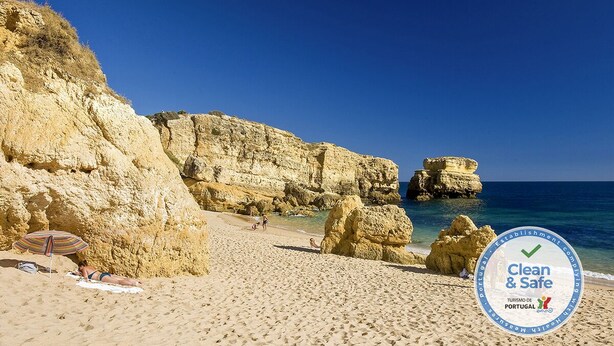 A beach with rocky formations and clear blue water.