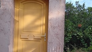 Una puerta amarilla con un escalón pequeño que lleva a ella, en una pared con textura.