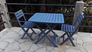 Un patio con suelo de piedra y una mesa y sillas de metal azul.