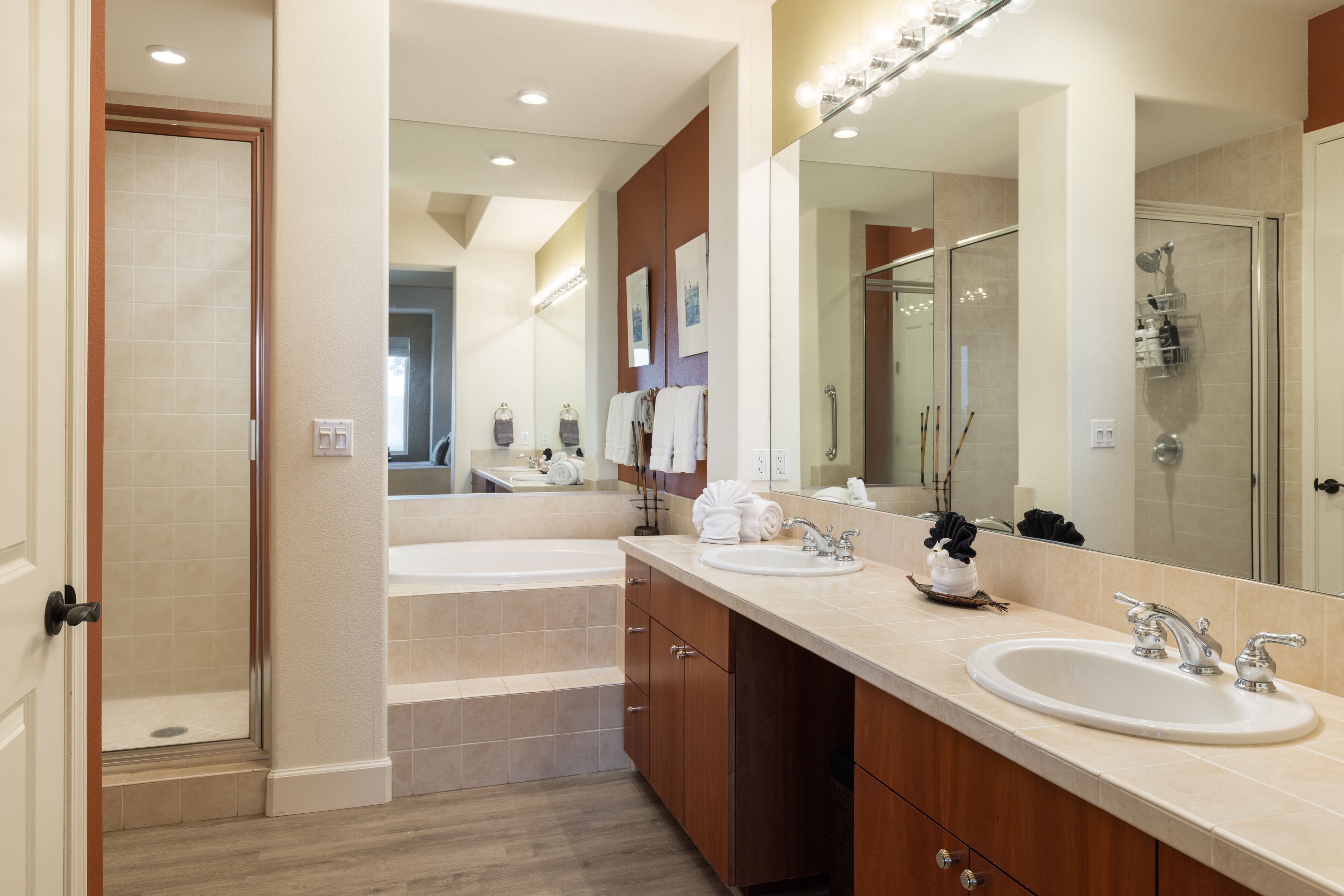 A modern bathroom with two sinks, a large mirror, and a walk-in shower.