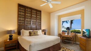 Quarto com cama grande, escrivaninha, cadeira, televisão e janela com vista.