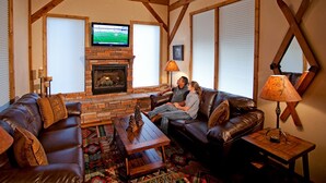 Una sala de estar acogedora con sofás de cuero, chimenea y televisor.