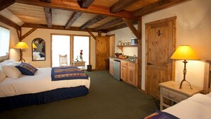 Un dormitorio con una cama, lámparas de noche, una mesita pequeña y vistas a una zona de cocina.
