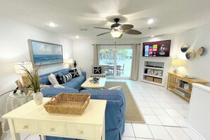 Ein Wohnzimmer mit Sofa, Couchtisch, Fernseher und Deckenventilator.