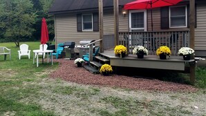A house with a deck, outdoor furniture, and potted flowers. - Quiet Beautiful Cabin in the Woods (Fall Brook)
