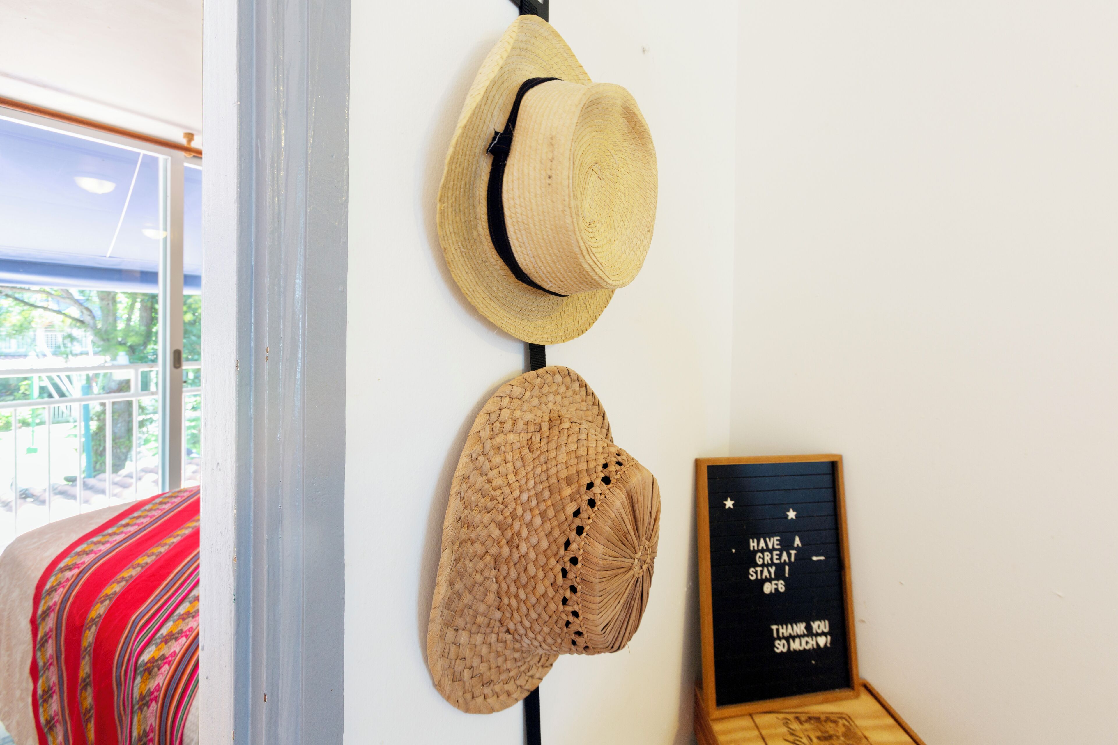 Una pared con dos sombreros colgados y un cartel enmarcado con un mensaje.
