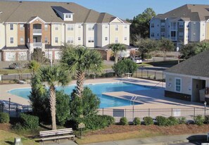 Residents enjoy a pool area with a deck and bench.