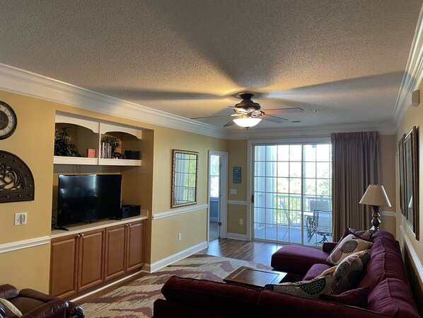 Relax in this inviting living room with a sofa, television, and ceiling fan.