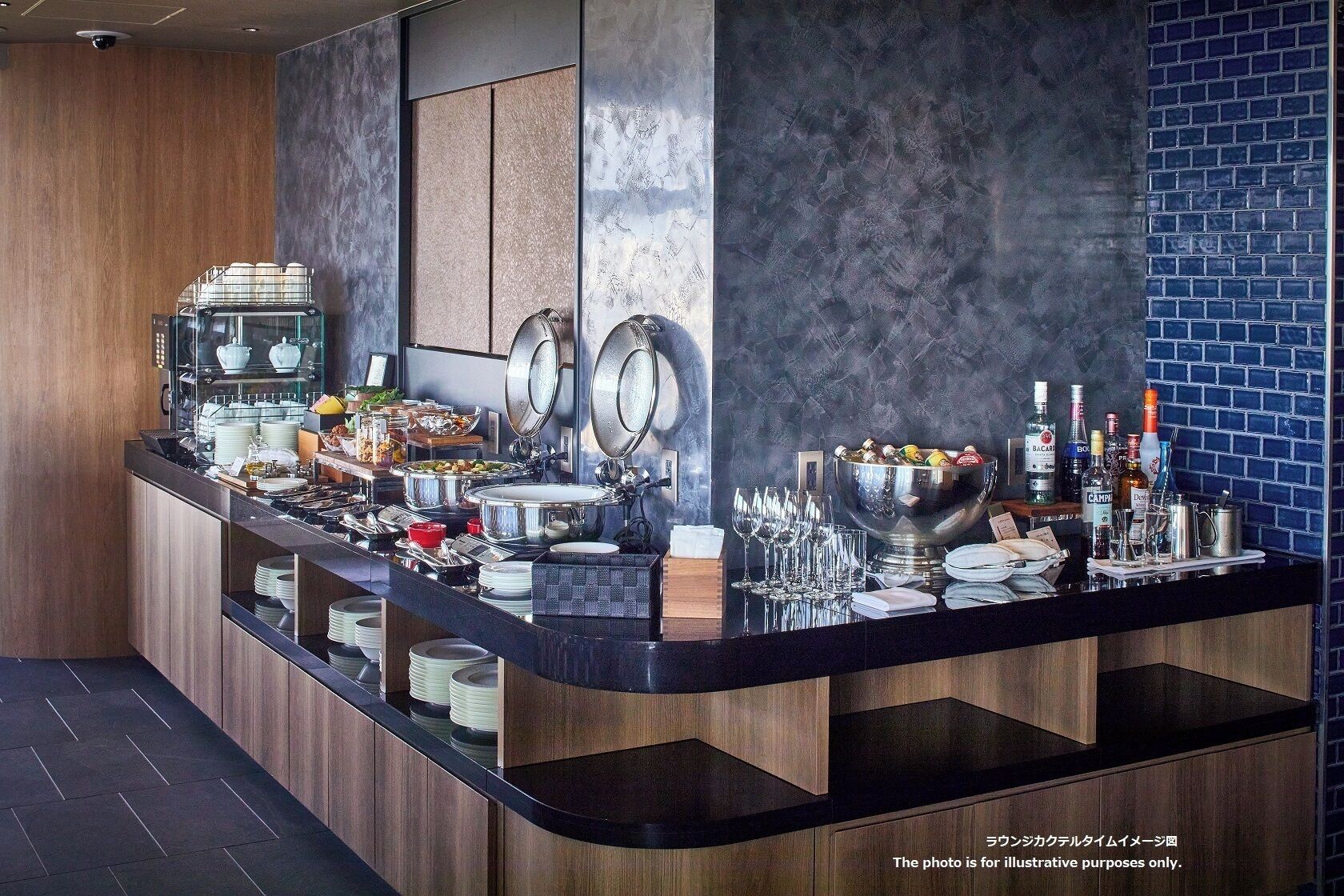 A modern bar area with a variety of food and drink options, including a buffet with multiple dishes and a large bowl of ice cream.