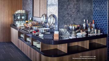 A modern bar area with a variety of food and drink options, including a buffet with multiple dishes and a large bowl of ice cream.
