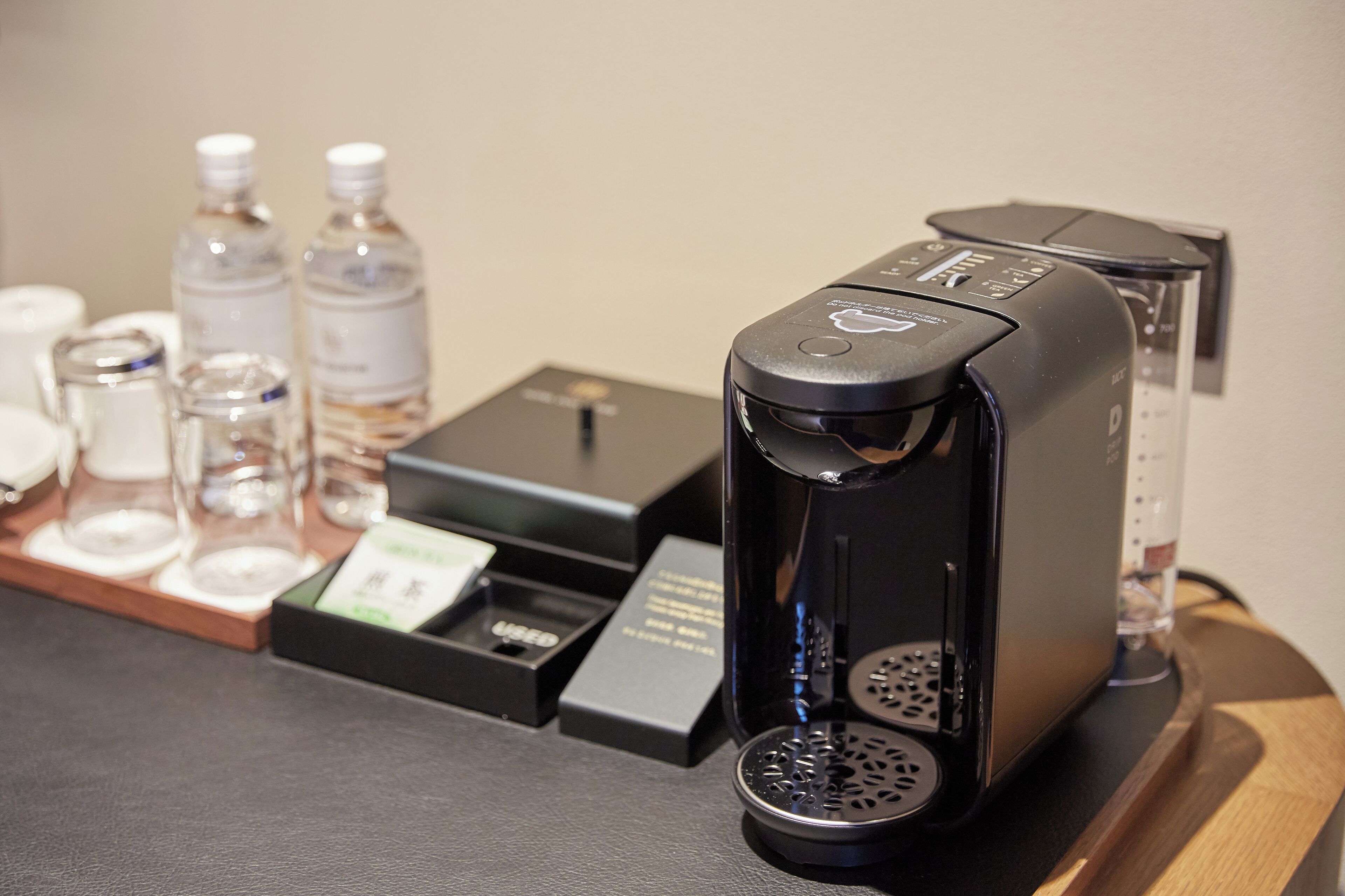 A coffee machine on a counter with a tray of water bottles and a coffee pod.